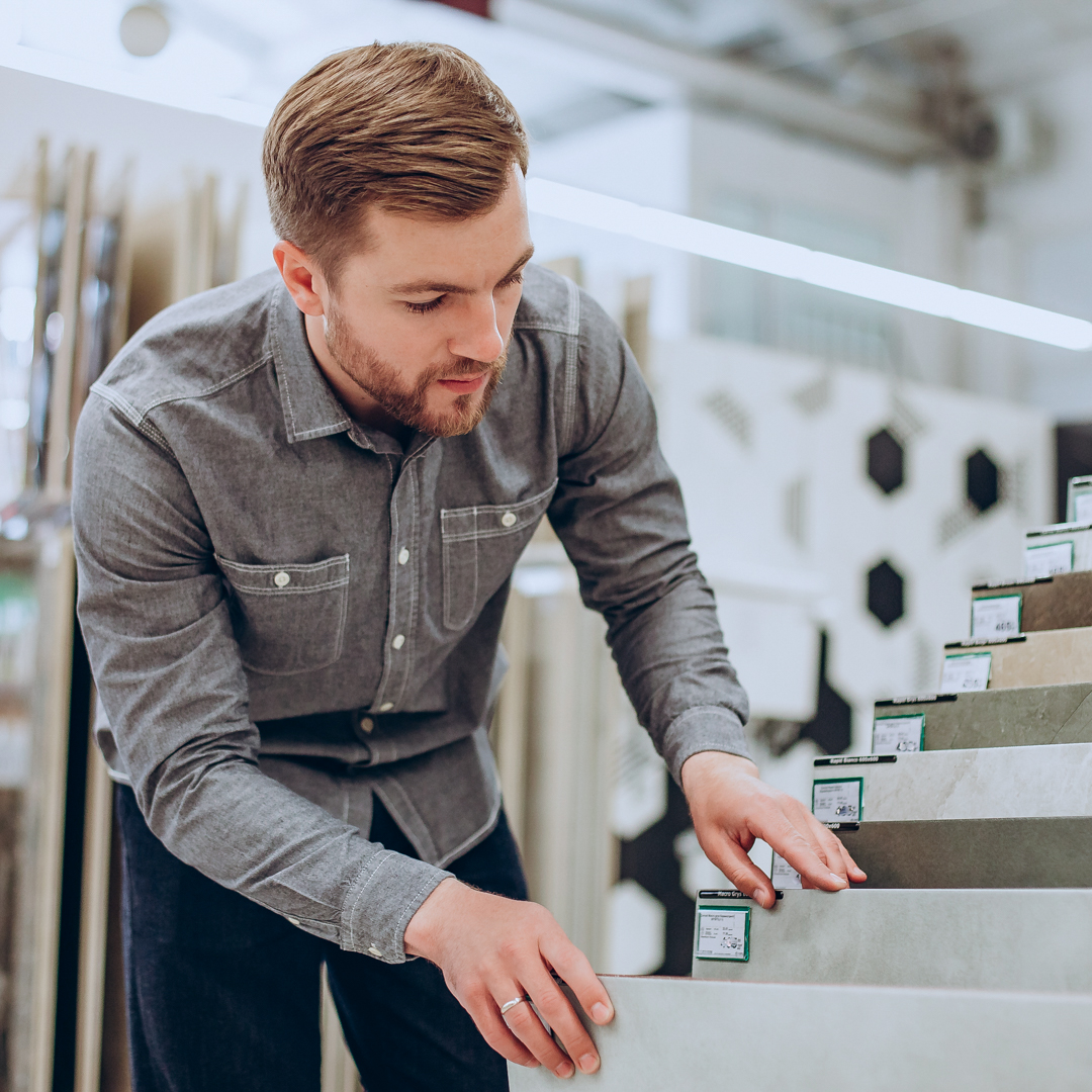Young man choosing tiles at building market